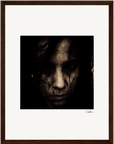 A close-up, dark-toned portrait of a face, partially obscured by shadows and dark hair, centered on a white background within a gallery-quality frame. A signature is visible on the lower right side—an inspirational wall art fine art print.