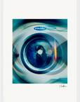 A close-up photo of an Electrolux washing machine door with blue and orange light reflections. The image has a soft, artistic blur and a signature at the bottom right—perfect for mindful home decor or inspirational wall art.
