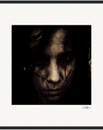 A close-up, dark-toned portrait of a person with long hair partially covering their face, looking directly at the camera with a serious expression. This fine art print is presented in a gallery-quality frame and signed in the lower right corner.
