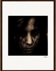 A dark, grainy portrait of a person with long hair partially covering their face, looking intently at the camera. This framed wall art features a thick white border and a brown wooden frame, perfect for conscious interior design.