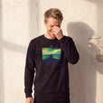 Calm - "Emerald Storms" Black Sweatshirt worn against a sunlit plaster wall