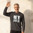 Compassion - "The Space We Share" deep charcoal grey Sweatshirt worn against a sunlit plaster wall