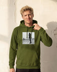 Compassion - "The Space We Share" Army Hoodie worn against a sunlit plaster wall