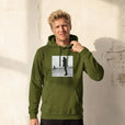 Compassion - "The Space We Share" Army Hoodie worn against a sunlit plaster wall