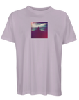 A light purple t-shirt featuring a small, square art print on the chest that shows a silhouette of a person standing with arms raised against a colorful, cloudy sky.