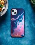 A smartphone with a blue and pink marbled case labeled INTENTION lies on a blue surface. This photo art captures unique textures, with pasta on one side and leafy greens on the other—perfect as an art print.