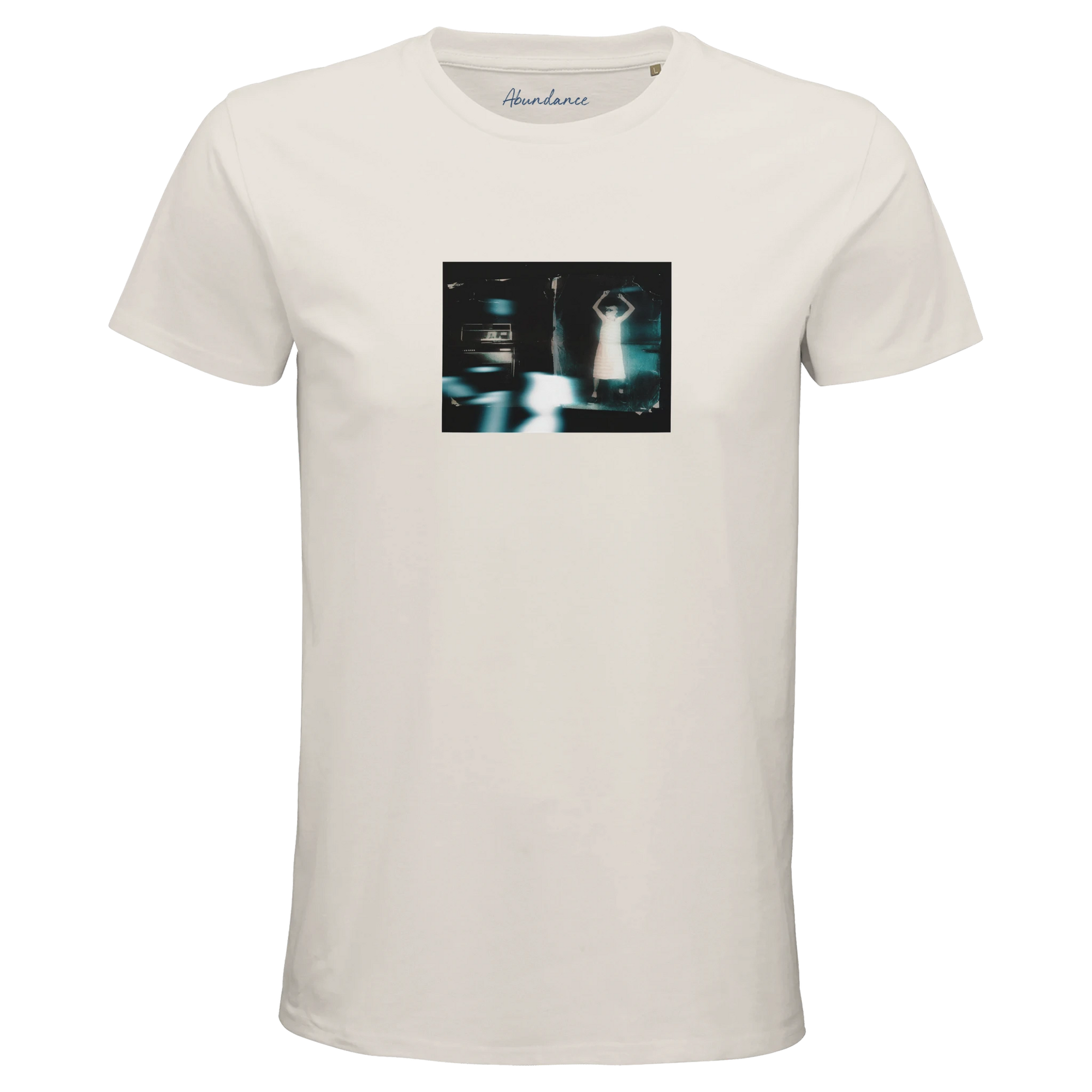 An off white short-sleeve t-shirt crafted from mindful apparel, featuring a rectangular graphic of a blurry, dark scene with a figure and two cars. "Abundance" is printed inside the collar.