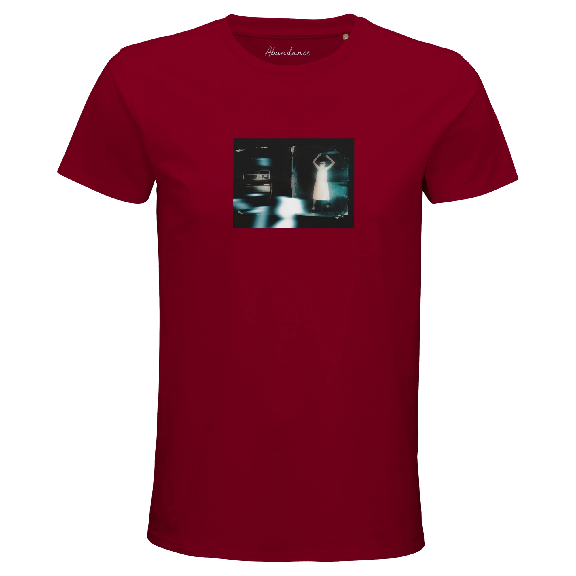 A burgundy short-sleeve t-shirt with a small, rectangular art graphic of a blurry figure and cars on the chest. "Abundance" is printed at the neckline, making this mindful piece both unique and expressive.