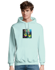 A young man wears a light blue hoodie from a mindful apparel collection, featuring a colorful graphic of two hanging sneakers against a multicolored background. He stands facing forward with a neutral expression.