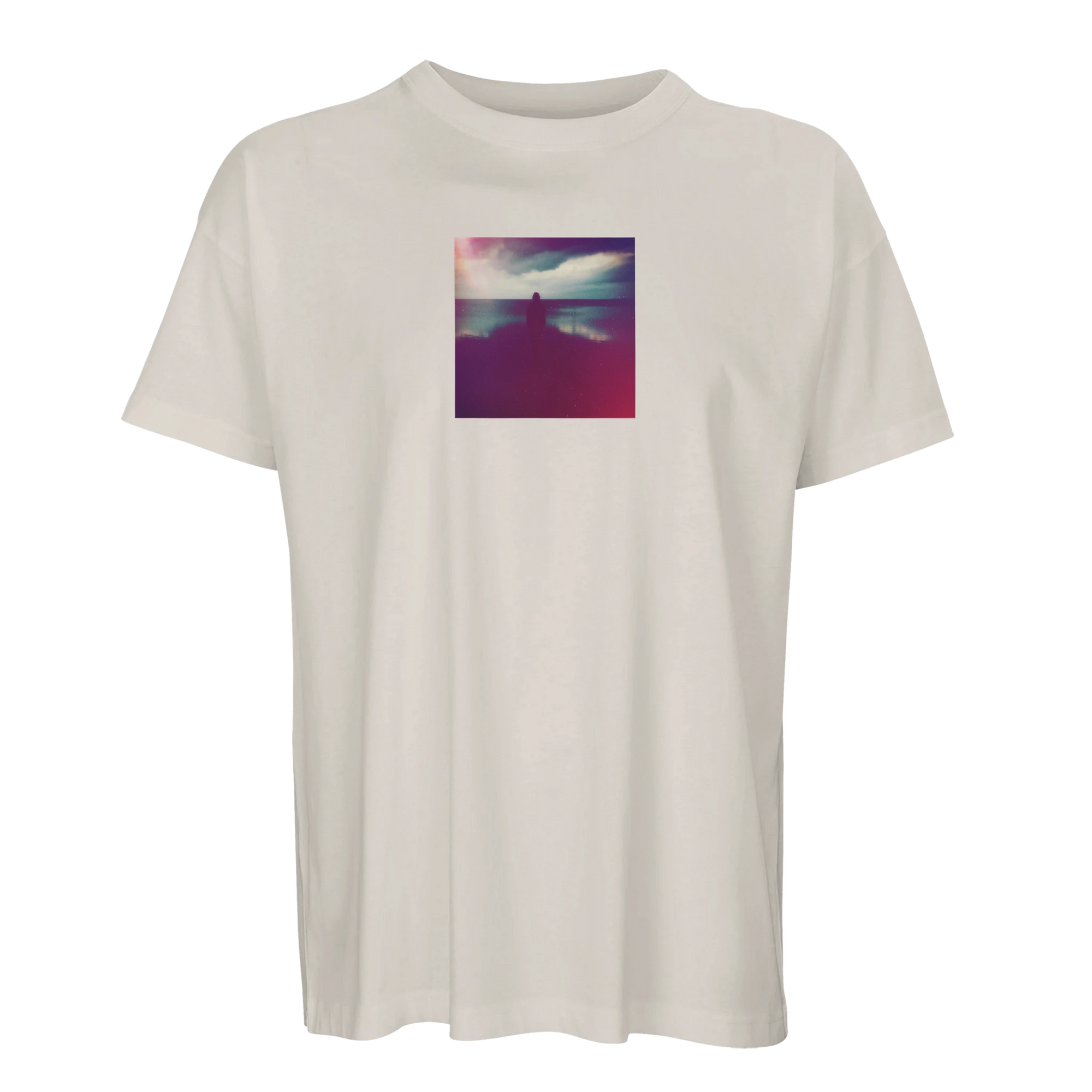 Off white short-sleeve t-shirt with a small, square, colorful art print on the chest showing a silhouetted figure by water under a cloudy purple and pink sky. Embrace conscious fashion with this unique design.