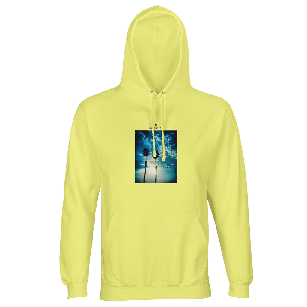 A light yellow hooded sweatshirt with an art print of two palm trees against a blue sky and sunlight filtering through branches, designed as mindful apparel for those who value style and conscious living.