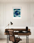 A home office with a wooden desk, brown leather chair, black desk lamp, plant, and telescope. Gallery-quality frame features modern abstract inspirational wall art in blue tones on a white wall between two sconces.
