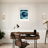 A home office with a wooden desk, brown leather chair, black desk lamp, plant, and telescope. Gallery-quality frame features modern abstract inspirational wall art in blue tones on a white wall between two sconces.