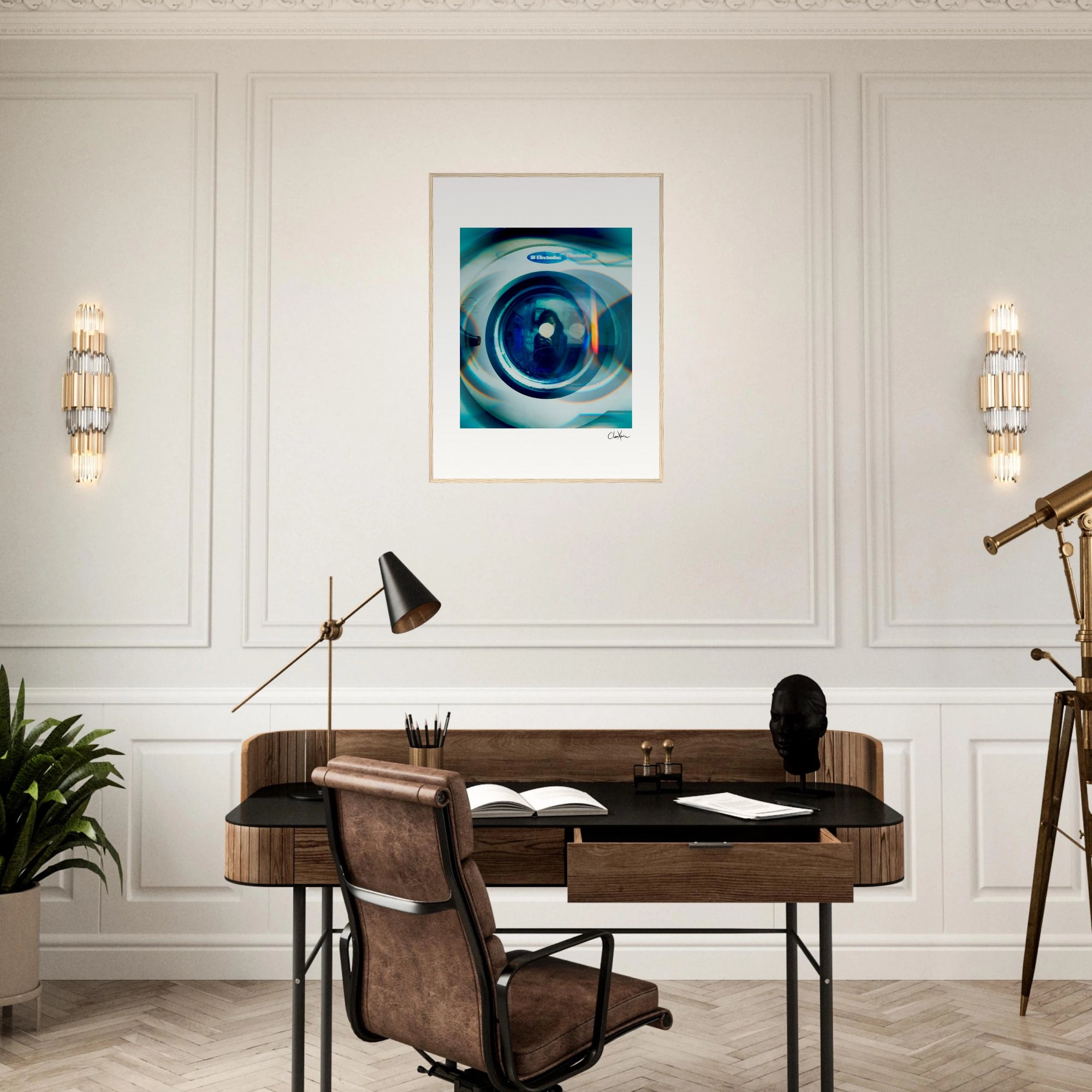 A home office with a wooden desk, brown leather chair, black desk lamp, plant, and telescope. Gallery-quality frame features modern abstract inspirational wall art in blue tones on a white wall between two sconces.