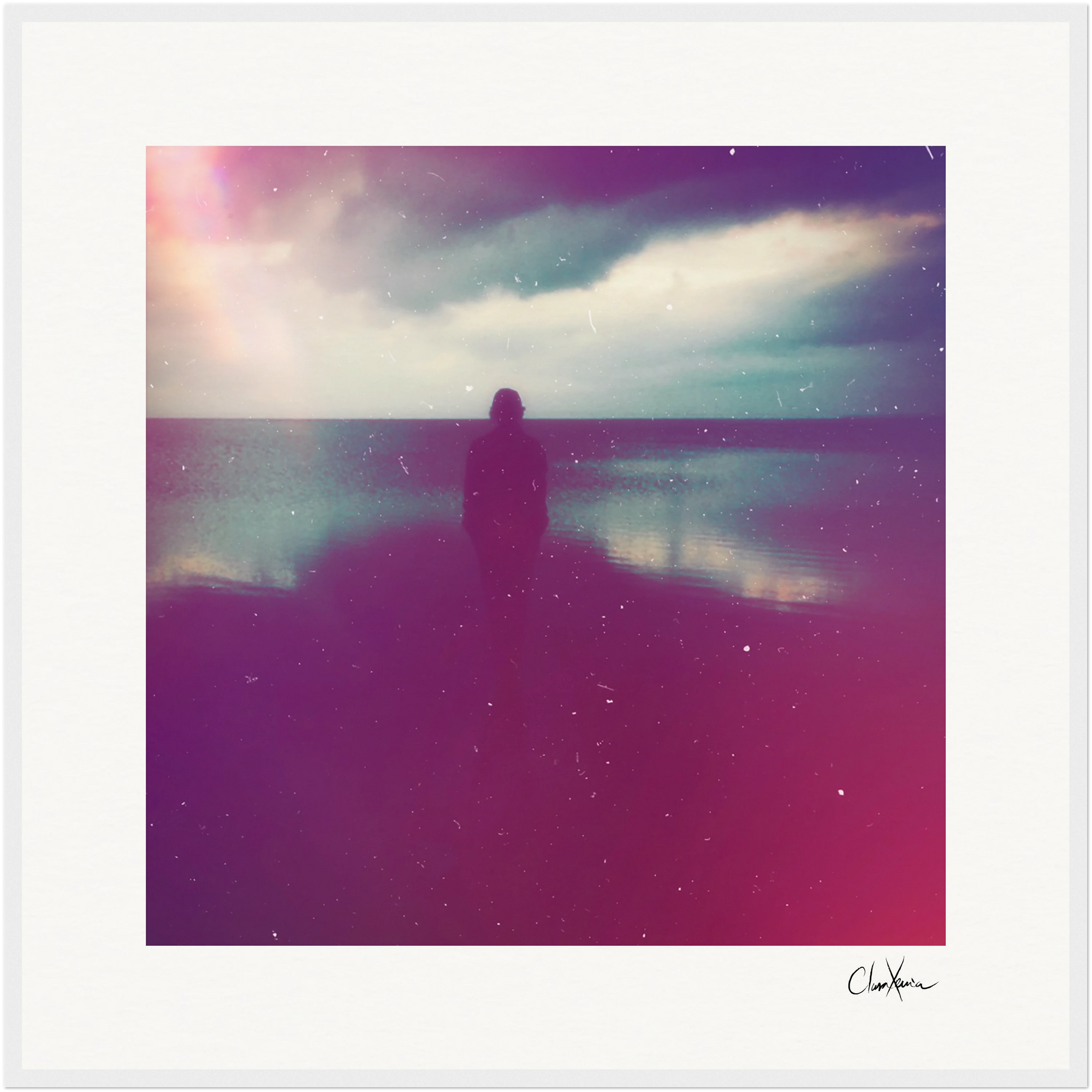 A silhouette of a person stands on a beach at sunset, facing the water beneath a cloudy sky with soft, colorful light in pink, purple, and blue hues. This fine art print features a grainy, dreamy texture—perfect for inspirational wall art.