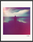 A silhouette of a person stands on a reflective beach beneath a cloudy sky. Pink and purple tints with visible grain and light streaks create a moody atmosphere, perfect as framed wall art for conscious interior design.