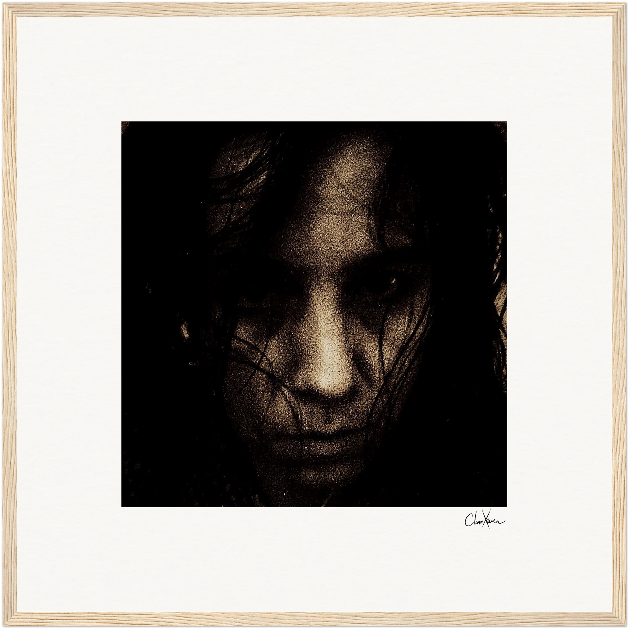A close-up, grainy, dark-toned photograph of a person's face with long hair partially covering the features, set against a light background and presented as fine art print in a simple light wood frame—perfect for conscious interior design.