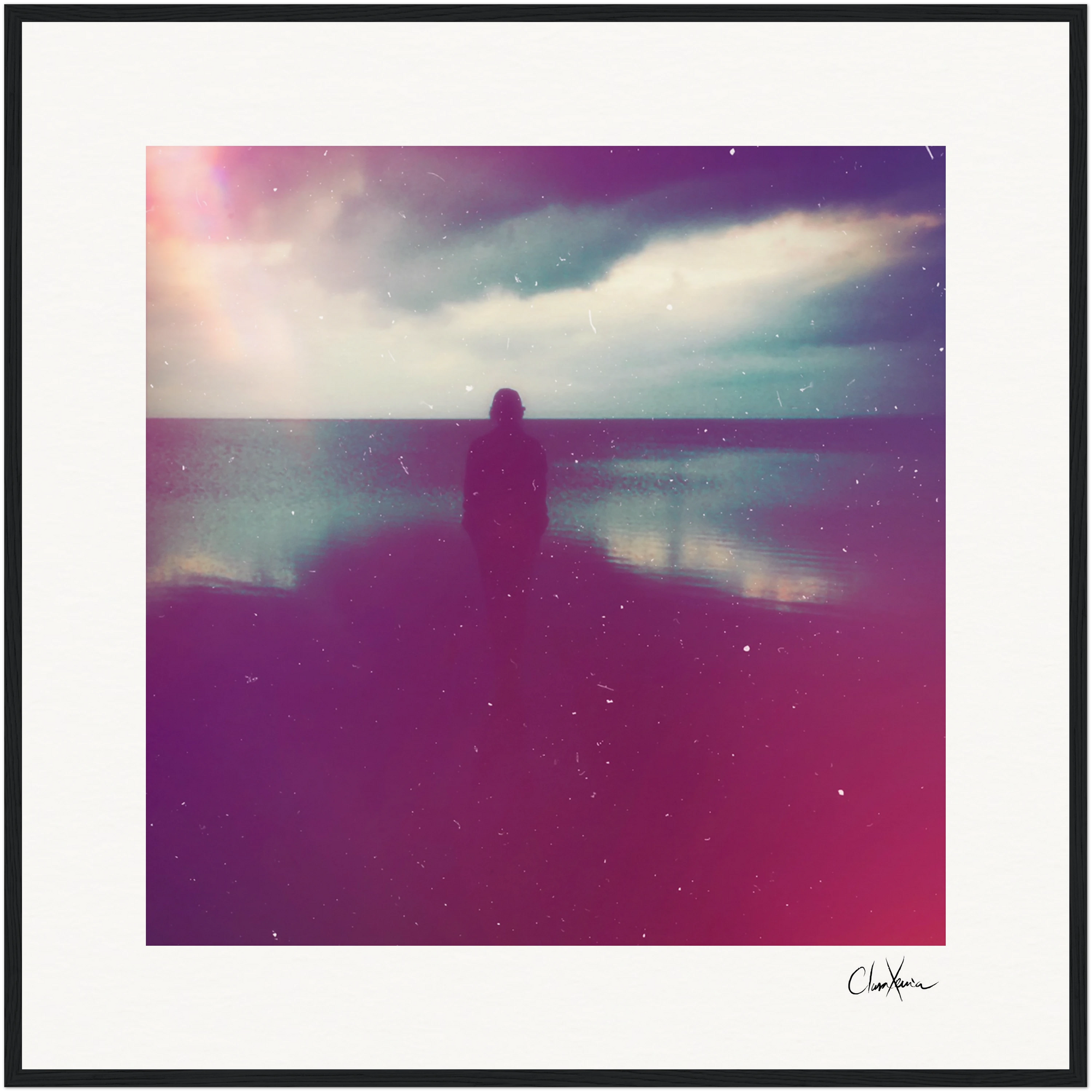 A silhouette of a person stands alone on a beach at dusk beneath a cloudy sky and faint rainbow. Soft pink and purple hues with a grainy texture enhance the dreamy effect, ideal as a fine art print for conscious interior design.