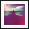 A silhouette of a person stands alone on a beach facing the ocean under a cloudy sky, with soft, colorful light effects and reflections in wet sand. This fine art print brings a dreamy, abstract quality to mindful home decor.