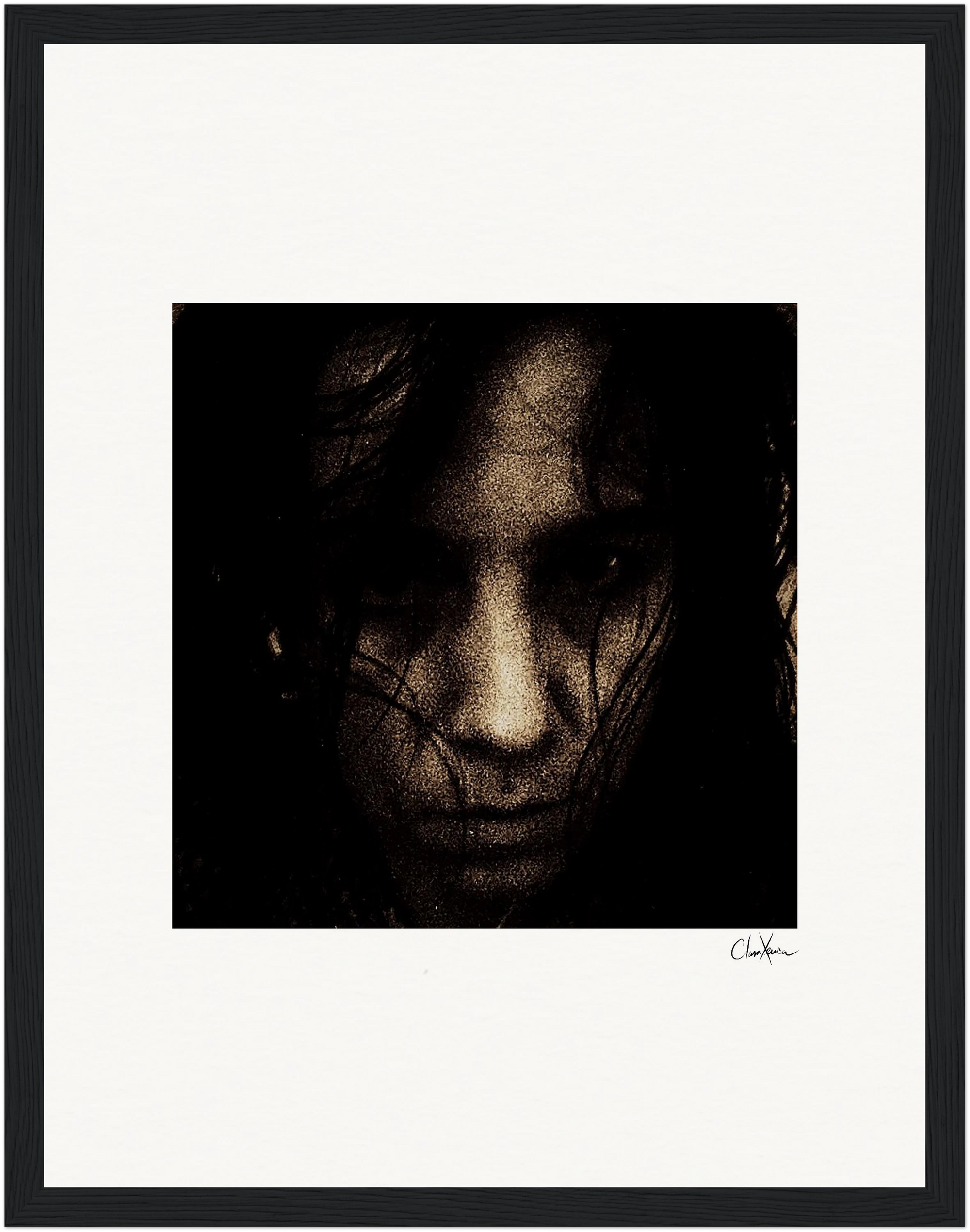 A dark, grainy close-up of a person’s face with long hair partly obscuring their expression, centered within a white mat and black frame—an evocative piece of framed wall art for conscious interior design.
