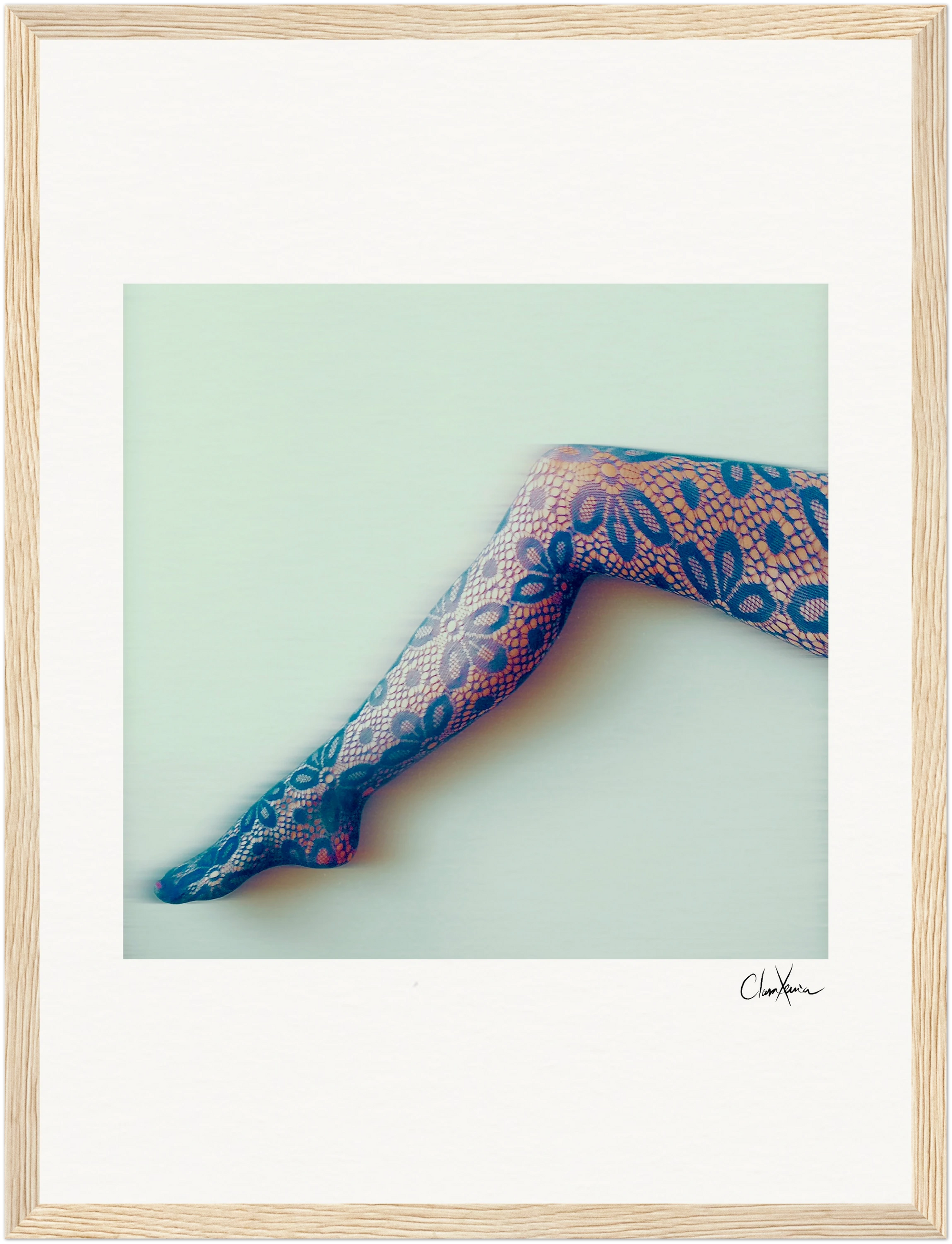 A single outstretched leg in patterned floral lace tights is set against a pale background with a soft, blurred effect. Framed in a gallery-quality frame, this piece brings mindful home decor to any conscious interior design. An artist’s signature appears below.