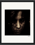 A close-up, grainy, sepia-toned portrait of a person with long dark hair partially covering their face, looking intently forward. This framed wall art adds depth and character to any mindful home decor or conscious interior design.