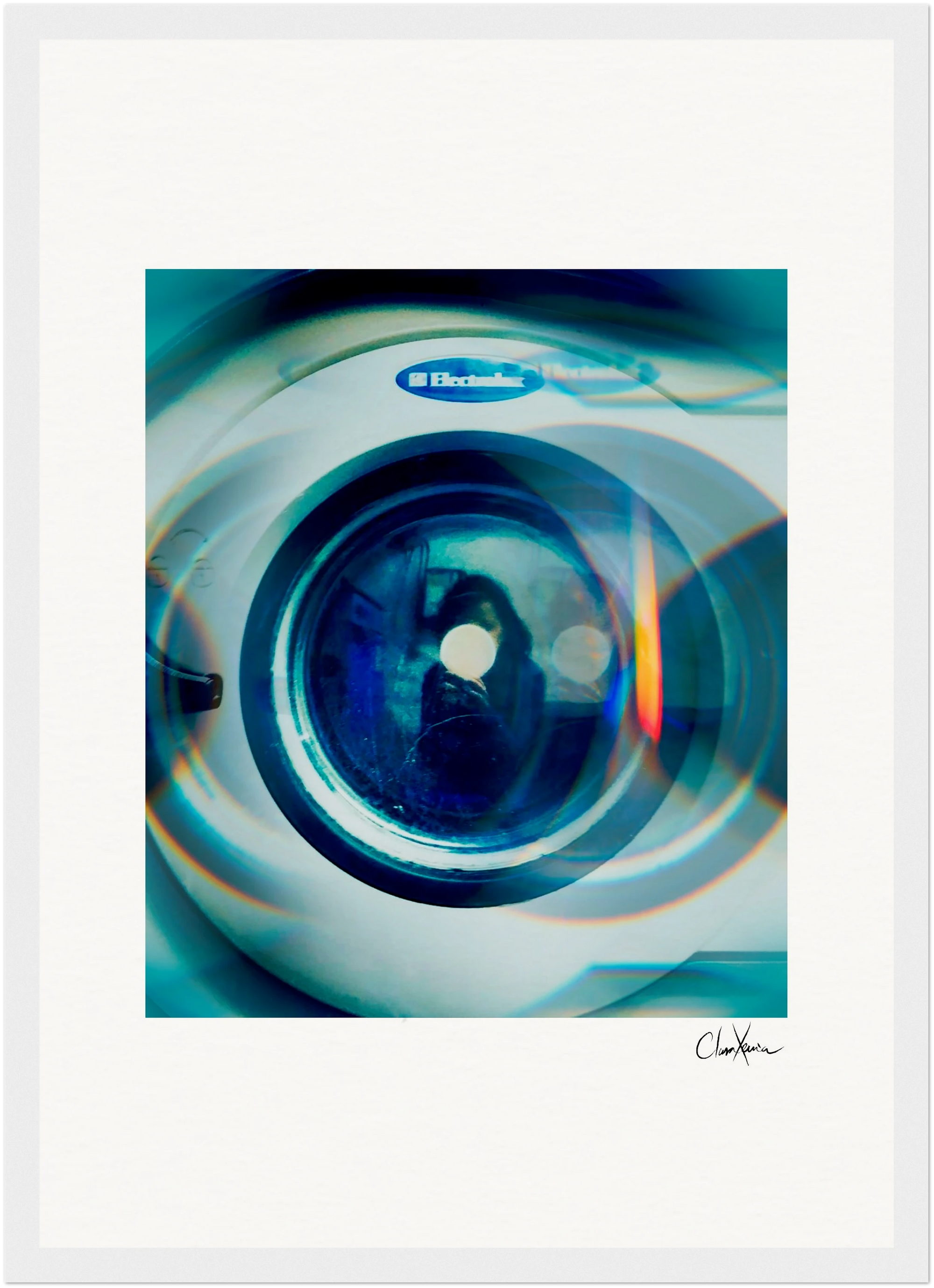 A close-up photo of an Electrolux washing machine door with blue and orange light reflections. The image has a soft, artistic blur and a signature at the bottom right—perfect for mindful home decor or inspirational wall art.