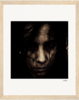 A grainy, high-contrast portrait of a person with long dark hair partially covering their face, gazing seriously at the camera, presented in a gallery-quality frame—perfect for conscious interior design.