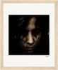 A grainy, high-contrast portrait of a person with long dark hair partially covering their face, gazing seriously at the camera, presented in a gallery-quality frame—perfect for conscious interior design.