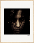 A grainy, dark-toned close-up of a person’s face with an intense expression, partially obscured by shadows and strands of hair, presented as framed wall art—perfect for mindful home decor and conscious interior design.