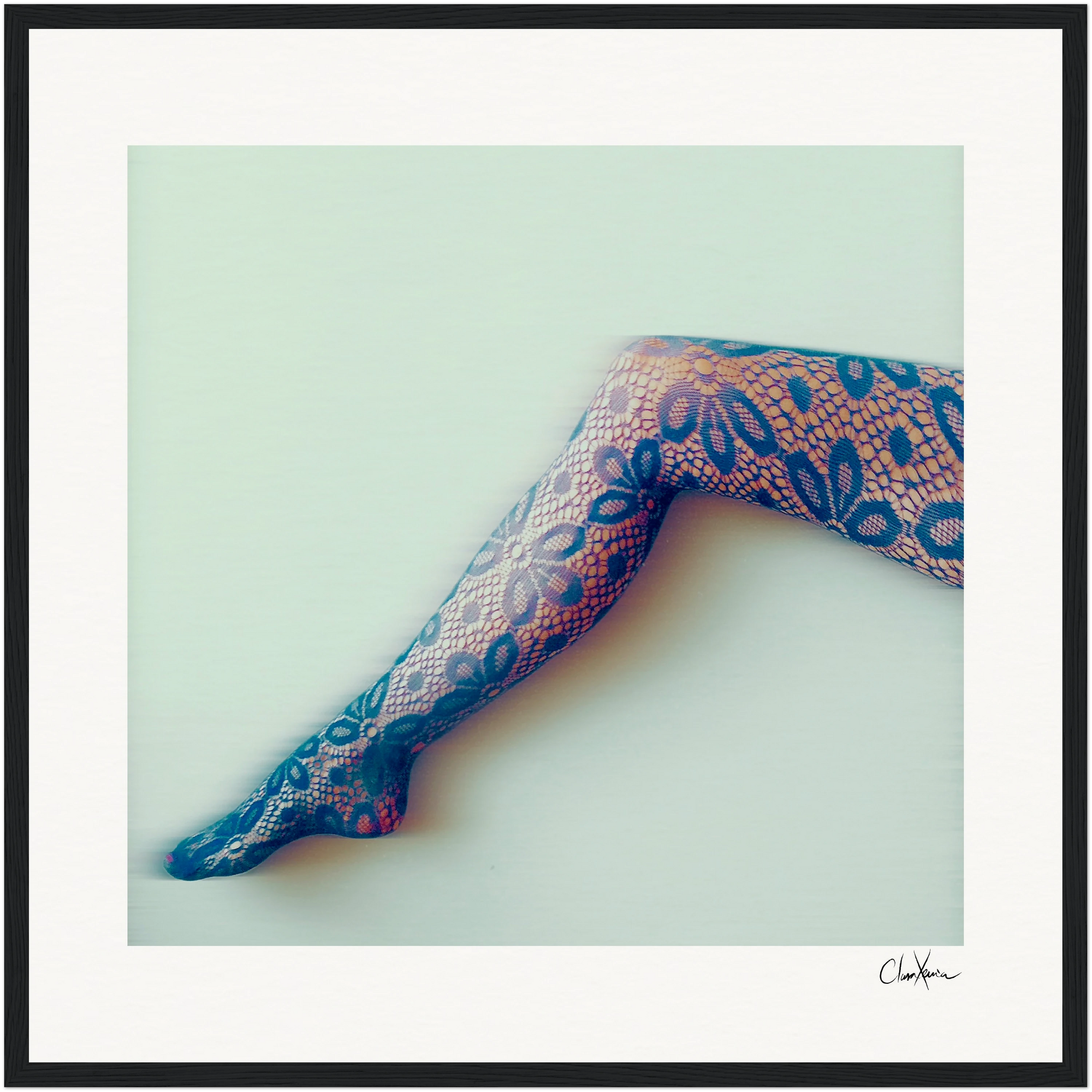 A single human leg extended diagonally, wearing patterned lace tights with a floral design, against a plain light background. The image is framed in a gallery-quality frame and signed in the bottom right—ideal for mindful home decor.