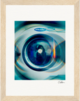A close-up photo of an Electrolux washing machine door, with reflections and blue light, artistically framed in a gallery-quality frame with white matting. This fine art print offers a striking, abstract touch to your wall decor.