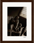Black and white photo of an older person sitting barefoot on a wooden chair, resting their head on one hand with a thoughtful expression. This fine art print is framed and signed at the bottom, perfect as inspirational wall art.