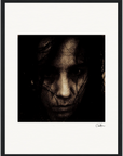 A grainy, close-up black and white photograph of a person’s face, partially obscured by dark hair and a serious expression. Centered on a white background with a gallery-quality frame and a signature at the bottom right, perfect for mindful home decor.