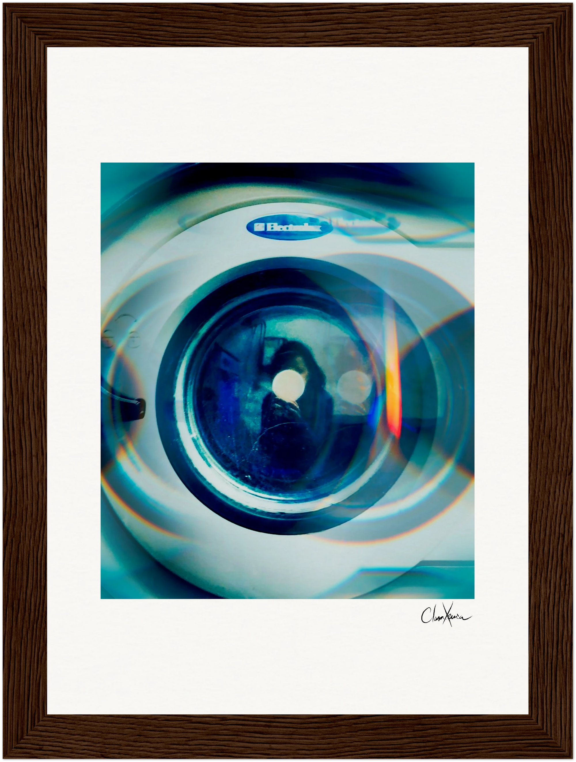 A close-up view of an Electrolux washing machine door with blue-toned lighting, framed as elegant wall art with a wide white matte and dark brown wooden frame—ideal for mindful home decor or as a fine art print. Signature in the lower right corner.