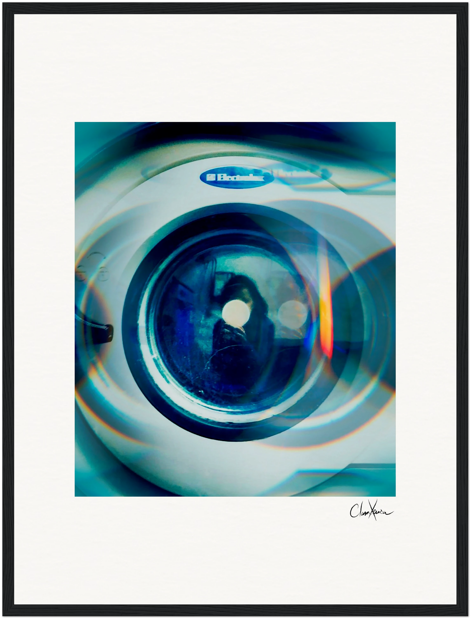 A close-up photo of the circular door of an Electrolux washing machine, viewed through a blue-tinted lens effect. This abstract, artistic piece is framed with a white mat and black border—perfect for mindful home decor or conscious interior design.