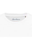 Close-up of the neckline of a plain white T-shirt, featuring "Abundance" in blue script on the inside collar. This mindful apparel piece includes a small brown size tag on the right, reflecting conscious fashion values.