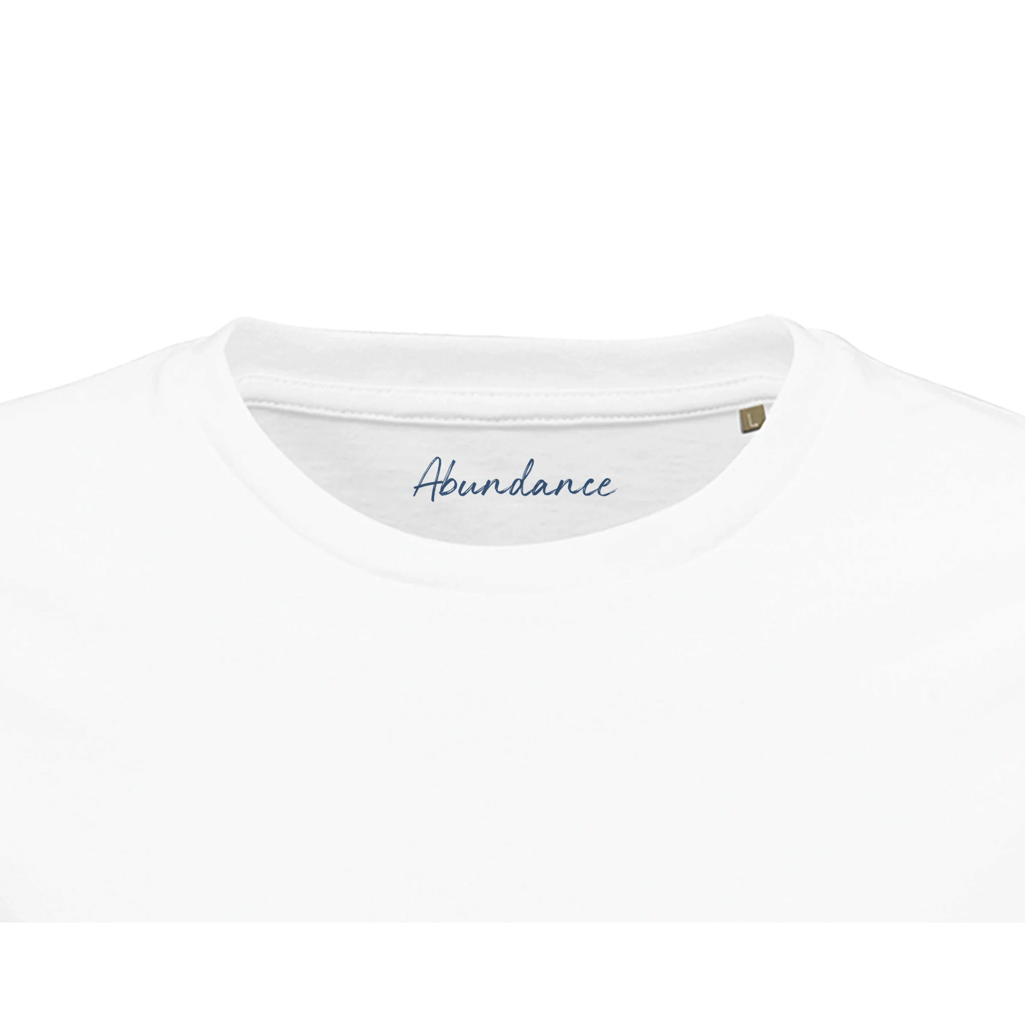 Close-up of the neckline of a plain white T-shirt, featuring "Abundance" in blue script on the inside collar. This mindful apparel piece includes a small brown size tag on the right, reflecting conscious fashion values.