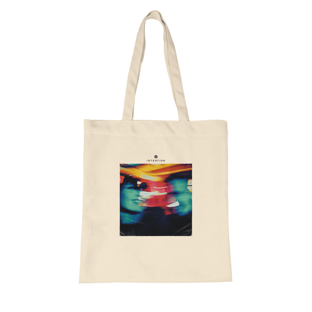 A natural tote bag with two long handles, made from organic material and featuring a colorful abstract image of two faces with "INTENTION" above—an ideal pick for mindful apparel lovers.
