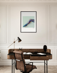 A modern home office featuring conscious interior design with a wooden desk, brown leather chair, black desk lamp, and mindful home decor. A fine art print of a patterned foot and ankle hangs above the desk, accented by wall sconces and a telescope.