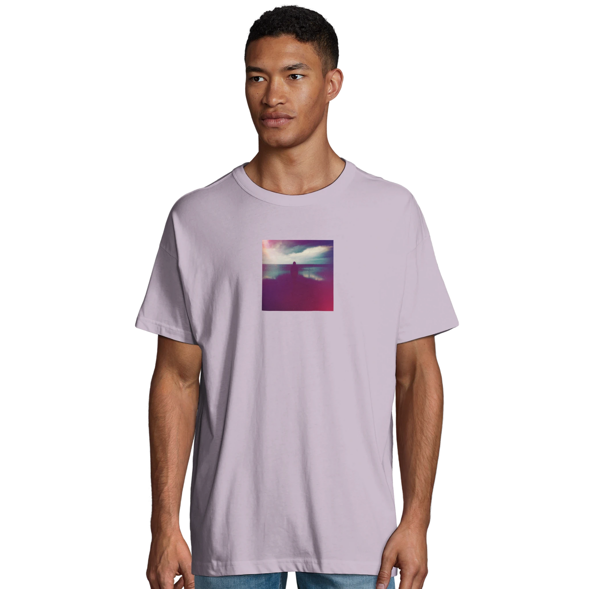 A man wears a light purple t-shirt featuring an art print of a colorful, abstract sunset on the chest, standing against a plain white background—perfect for those who value conscious fashion.