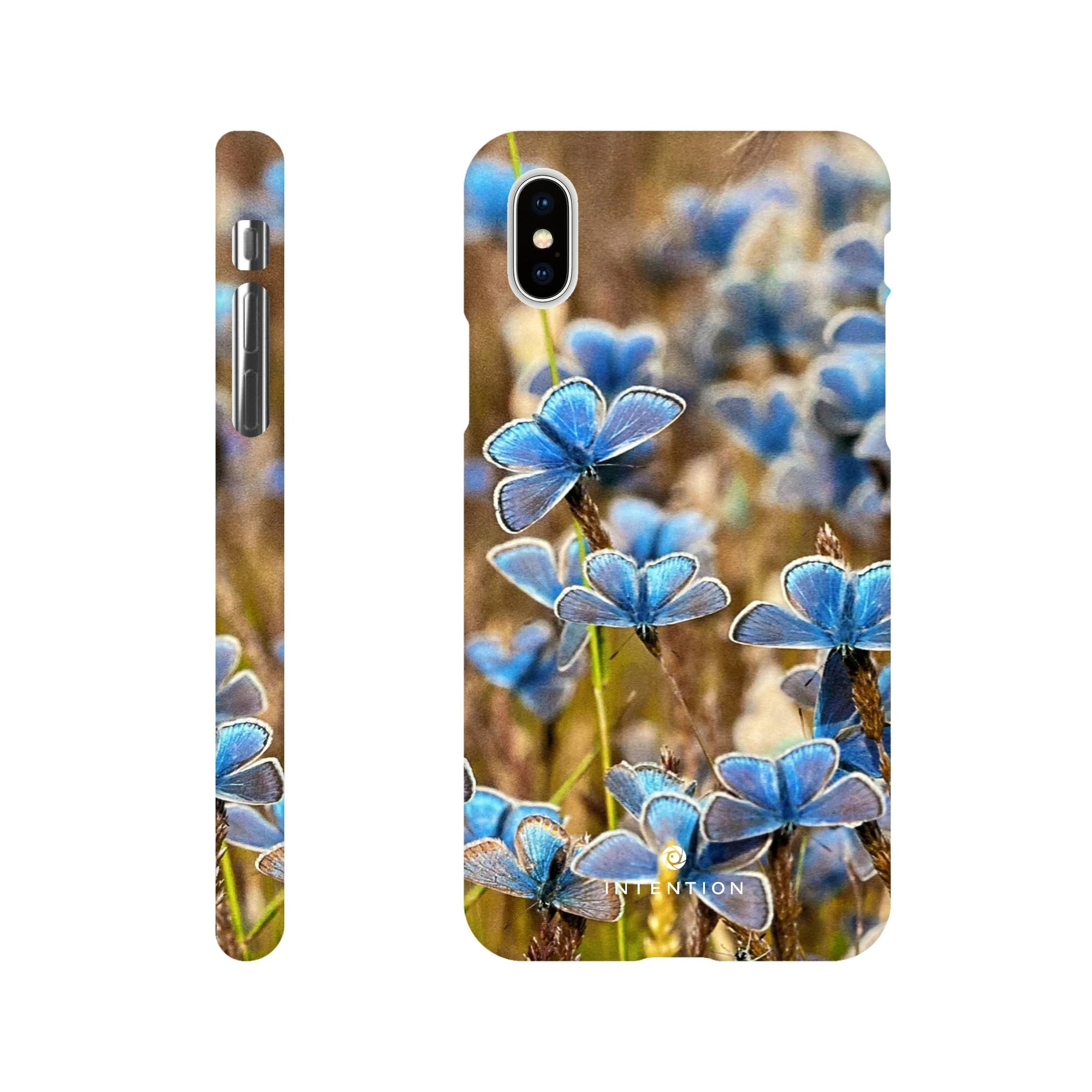 A phone case shown from the back and sides features a photo art pattern of blue butterflies resting on grass, with camera and button cutouts visible. The soft brown background enhances the textures, and the Inninoh logo is at the bottom.
