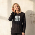 Compassion - "The Space We Share" Deep Black Long Sleeve worn against a sunlit plaster wall