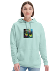 A woman with straight brown hair wears a light blue hoodie featuring an art print on the chest, paired with light blue jeans. She stands against a plain white background, showcasing mindful apparel.