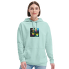 A woman with straight brown hair wears a light blue hoodie featuring an art print on the chest, paired with light blue jeans. She stands against a plain white background, showcasing mindful apparel.
