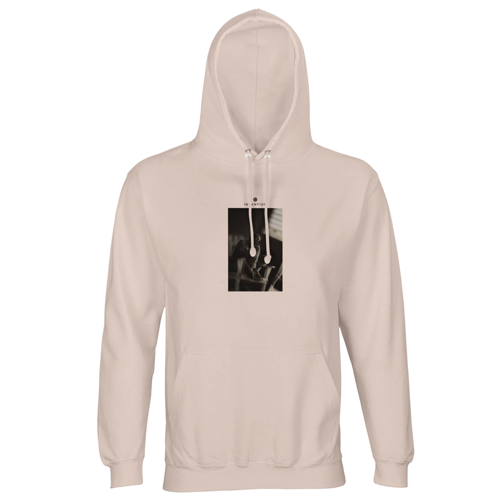 A creamy pink hooded sweatshirt with a front pocket, featuring a rectangular graphic of metal tools on the chest—crafted for those who appreciate conscious fashion.