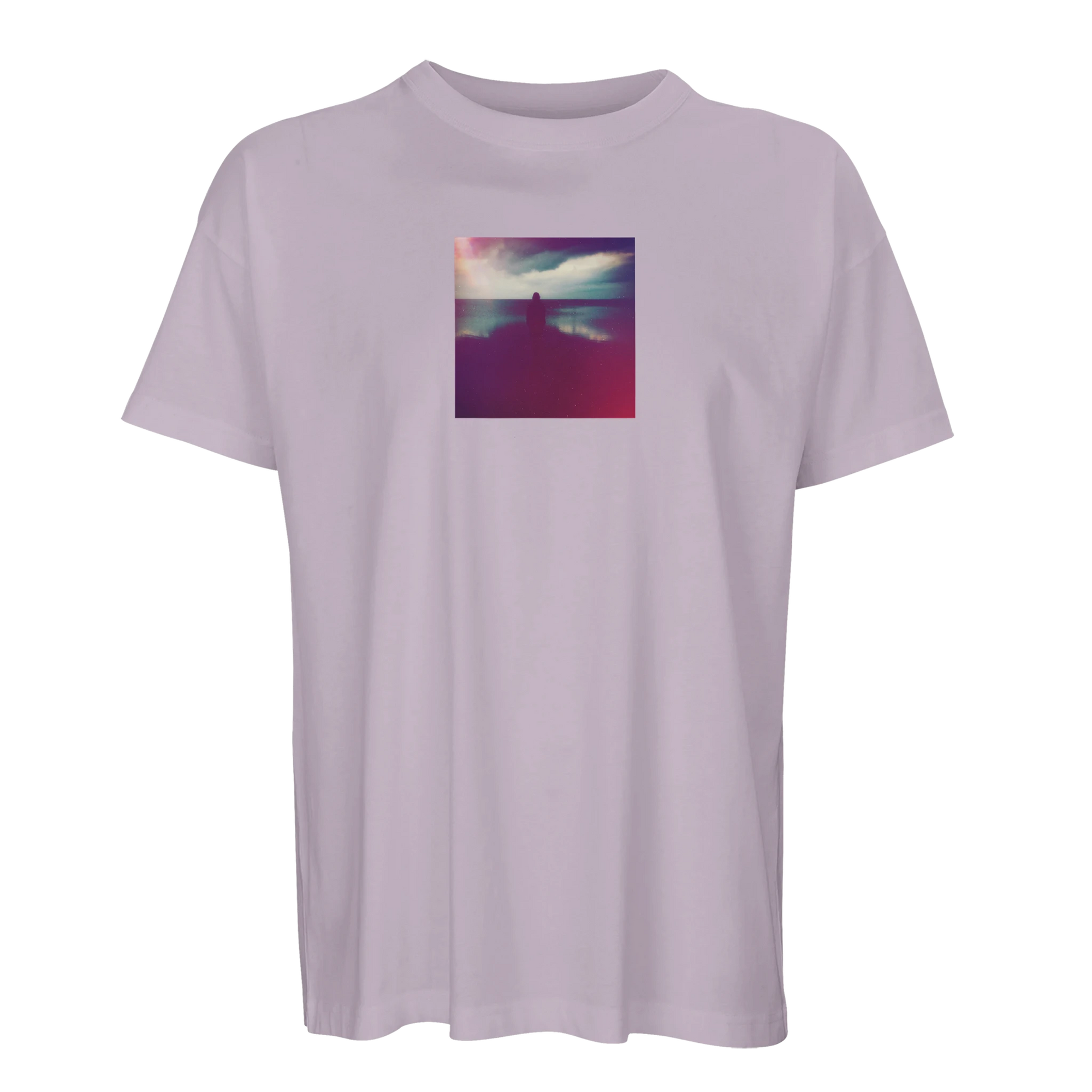 A light purple t-shirt featuring a small, square art print on the chest that shows a silhouette of a person standing with arms raised against a colorful, cloudy sky.