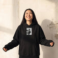 Fortitude - "Everyday Hero" Black Hoodie worn against a sunlit plaster wall