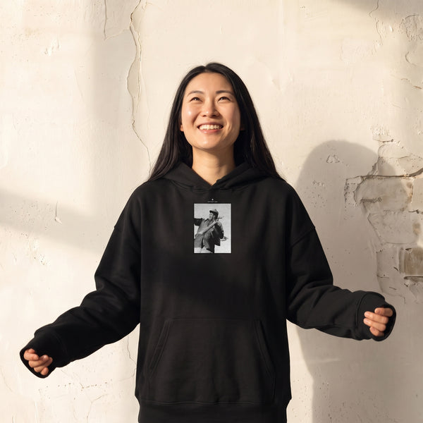 Fortitude - "Everyday Hero" Black Hoodie worn against a sunlit plaster wall