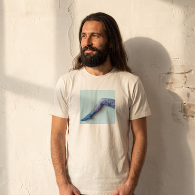 Jazzy - "Lacey Leg" Off White T-shirt worn against a sunlit plaster wall